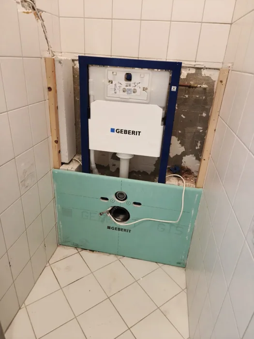 Geberit inbouwframe voor een hangtoilet met groene gipsplaat tussen witte wandtegels