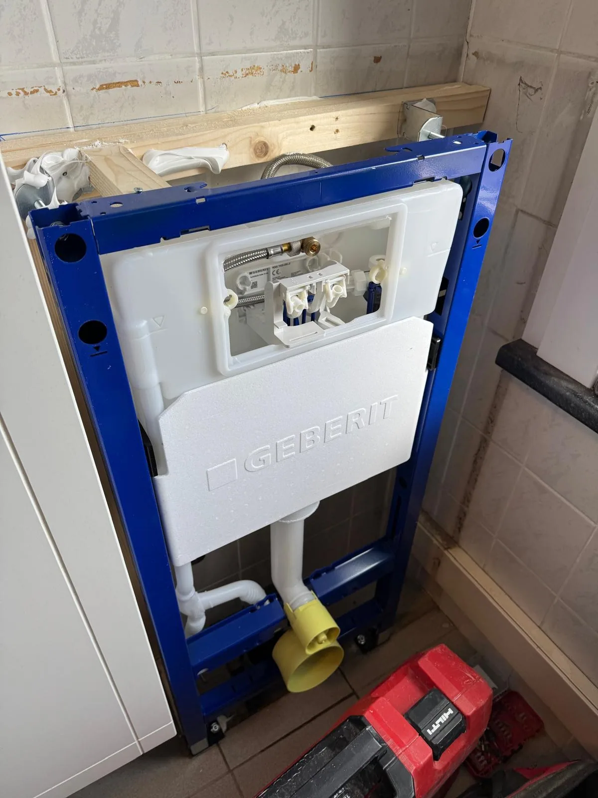 Inbouwreservoir in een blauw montageframe, geplaatst voor een hangtoilet