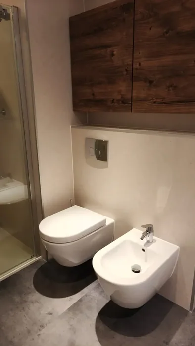 Hangtoilet en hangend bidet op een voorzetwand met een houtlook kast erboven