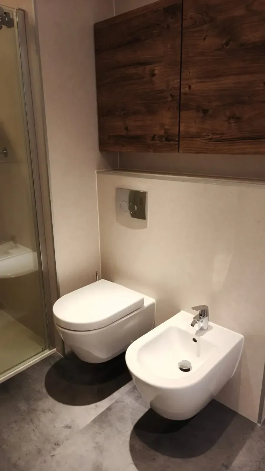 Hangtoilet en hangend bidet op een voorzetwand met een houtlook kast erboven