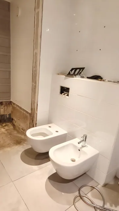 Wit hangtoilet en hangend bidet naast elkaar tegen een witte voorzetwand