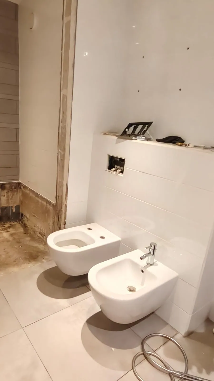 Wit hangtoilet en hangend bidet naast elkaar tegen een witte voorzetwand