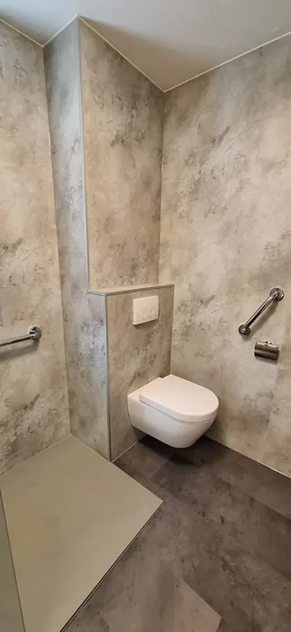 Hangtoilet op een voorzetwand met beige marmerlook wandpanelen en steunbeugels aan beide kanten