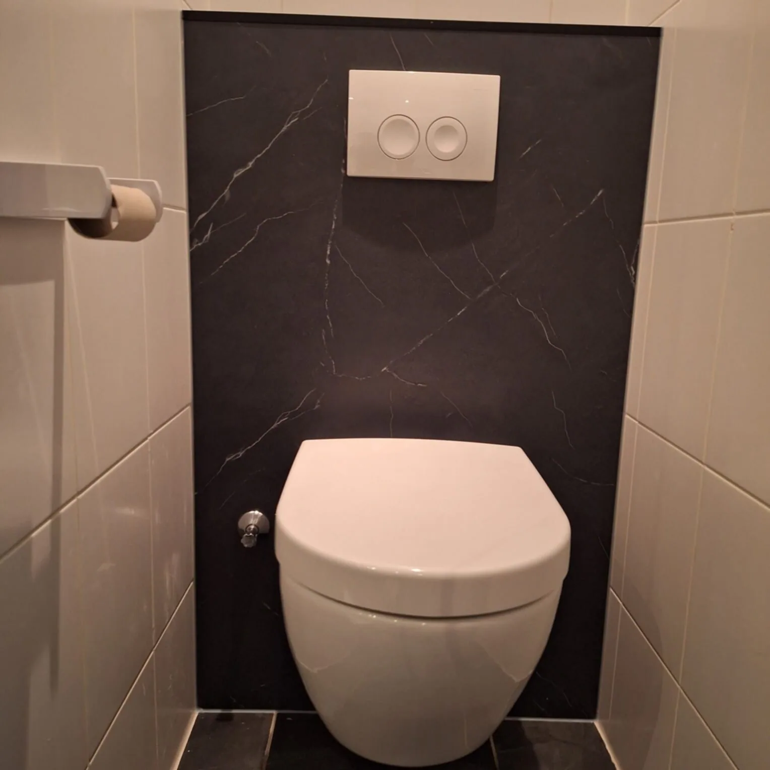 Hangtoilet tegen een voorzetwand met zwart marmerlook paneel en witte drukplaat
