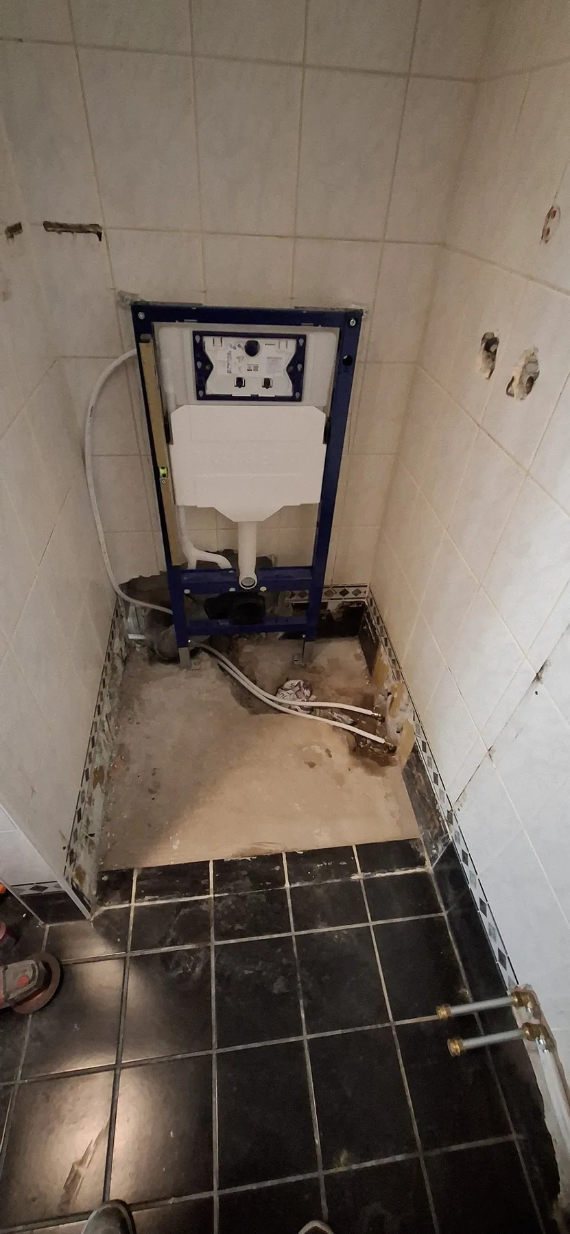 Inbouwreservoir voor een hangtoilet, geplaatst in een betegelde hoek tijdens de renovatie