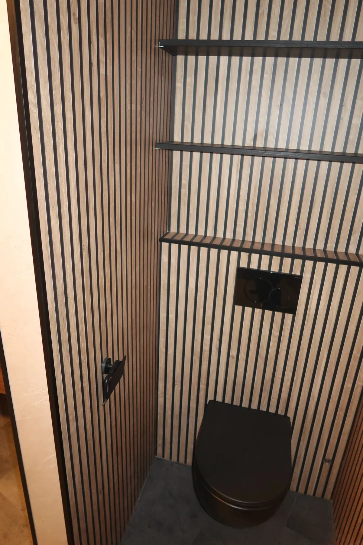 Toilet met houten lamellenwand, zwart hangtoilet en drie zwarte wandplanken