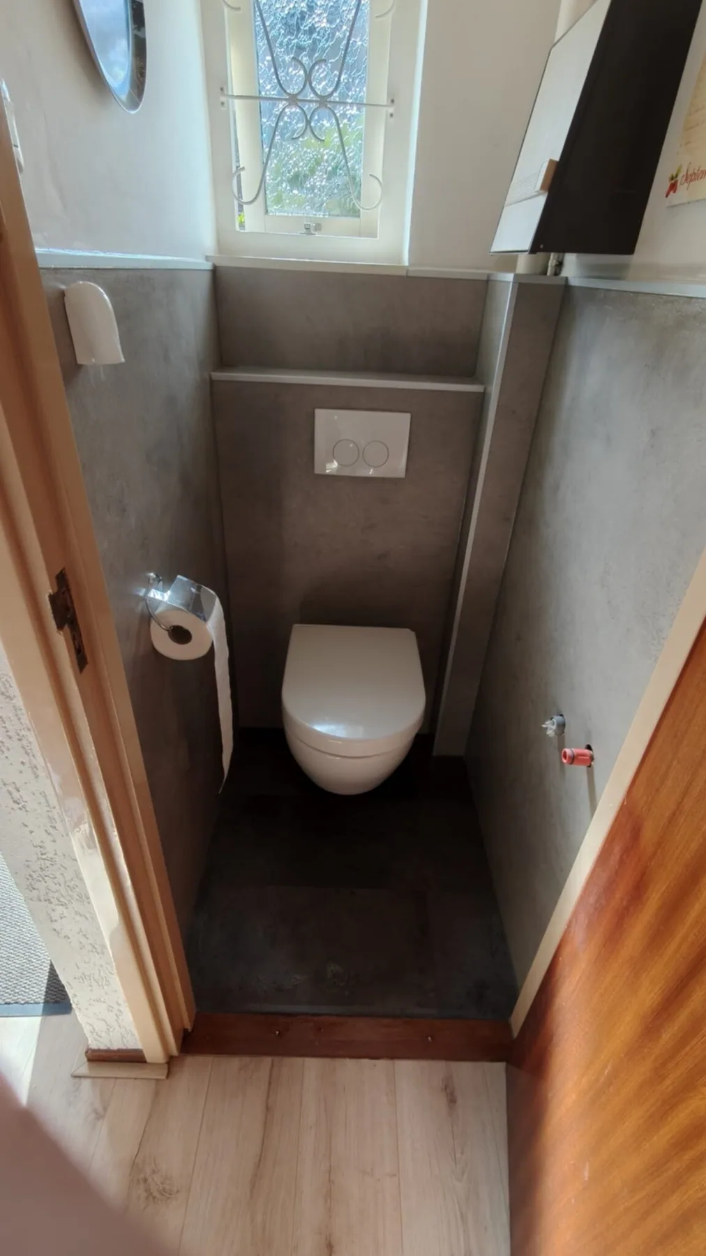 Gerenoveerde toiletruimte met hangtoilet en grijze betonlook wandpanelen
