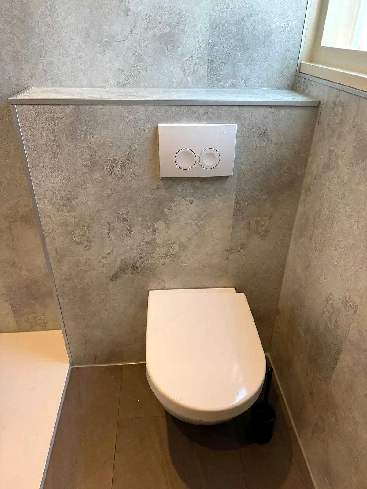 Zwevend toilet met voorzetwand in lichte betonlook