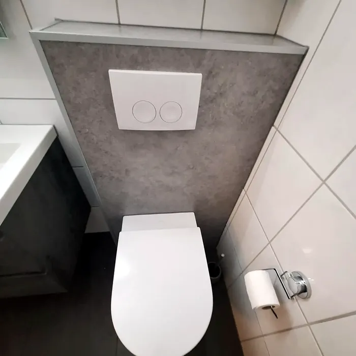 Hangtoilet met grijze voorzetwand en wit bedieningspaneel