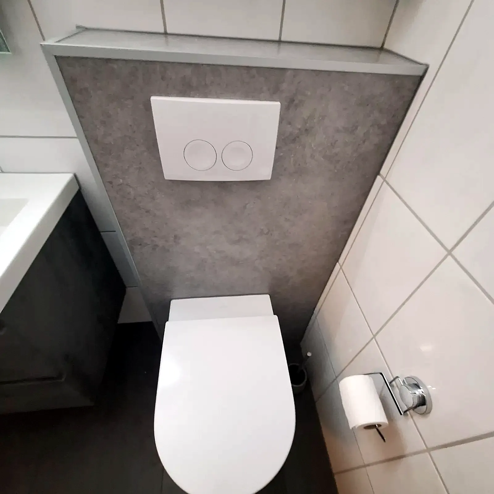 Hangtoilet met grijze voorzetwand en wit bedieningspaneel