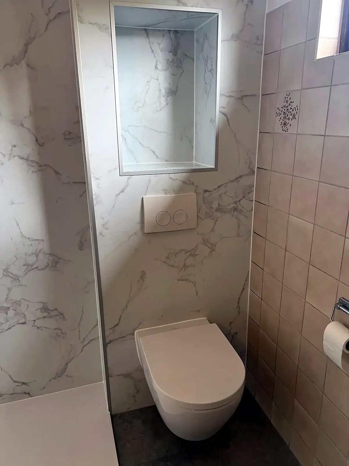 Hangtoilet in een witte marmerlook wand met inbouwnis