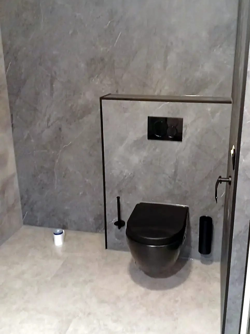 Zwart hangtoilet voor een grijze betonlook voorzetwand