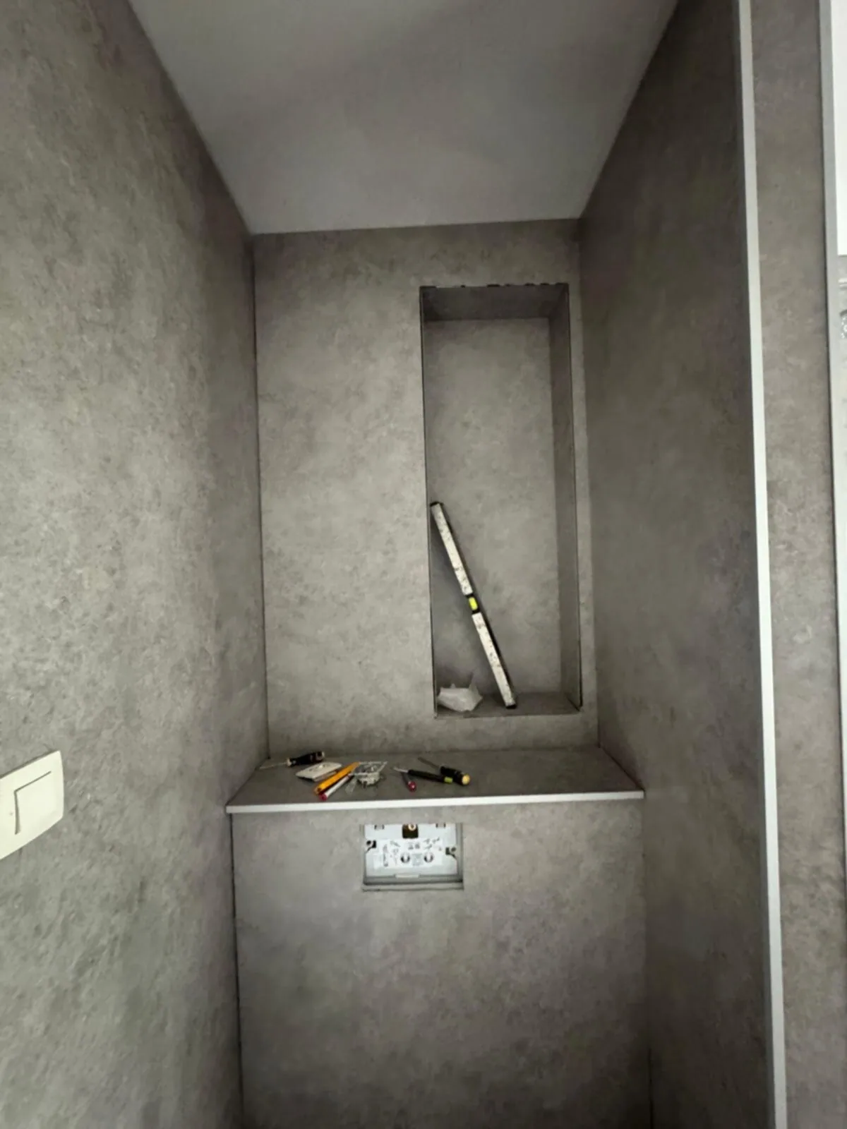 Voorzetwand voor een hangtoilet met nis, bekleed met grijze stenen-look wandpanelen